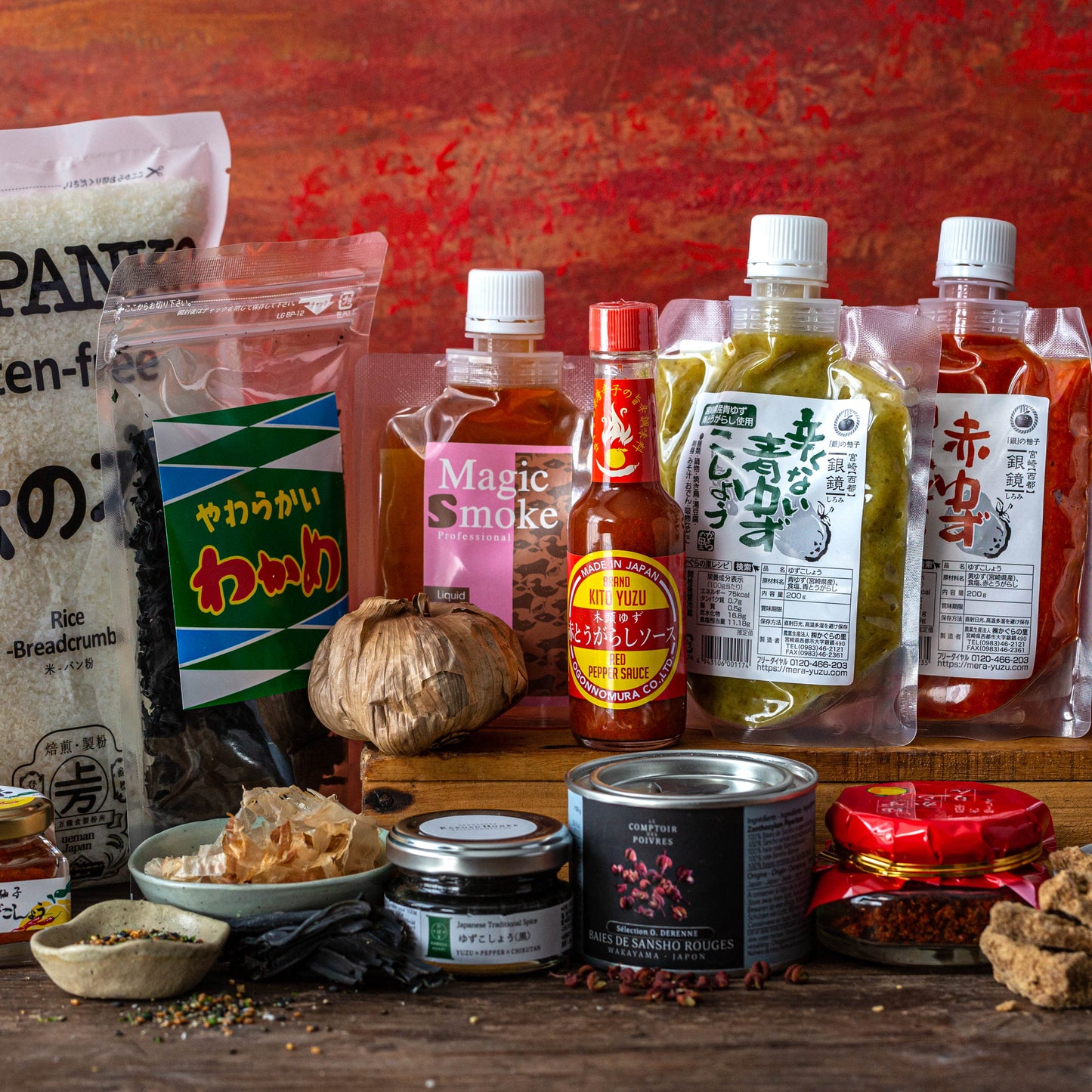 A variety of Japanese and Asian food ingredients, sauces, spices, and condiments arranged on a wooden surface against a red background.