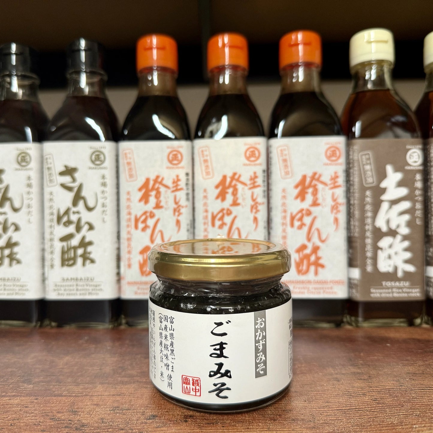 A 150g jar of Black Sesame Miso Paste with a white label is displayed on a shelf in front of several bottles bearing Japanese labels.