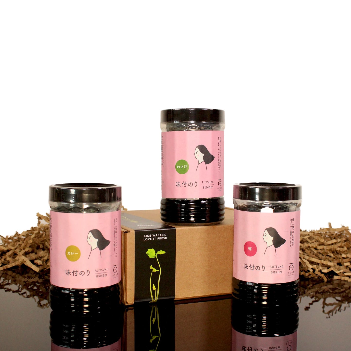 Three jars of Fukui Nori Snack Set with pink labels are arranged around a brown box on white and brown crinkle paper—perfect gluten-free snacks for exploring authentic Japanese flavours.