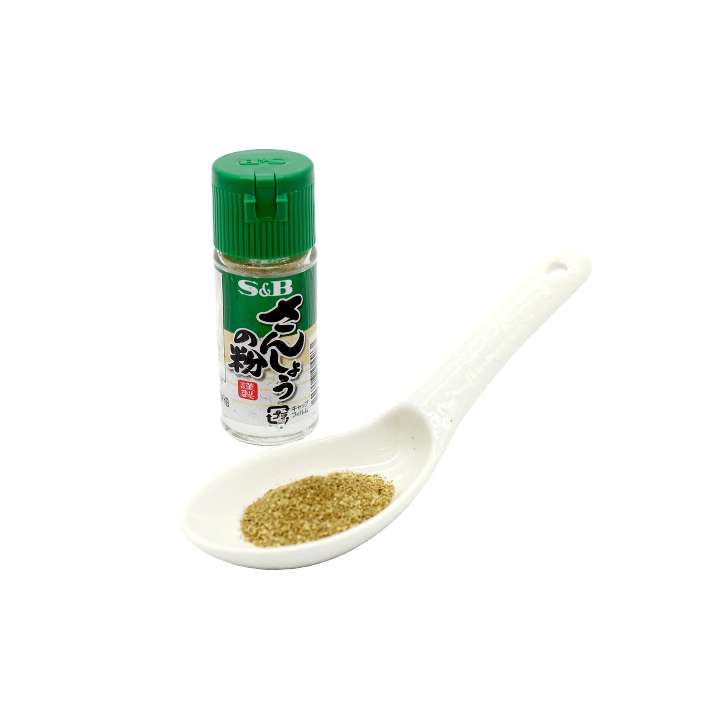 An 8g bottle of Ground Japanese Sansho Pepper with a green cap is shown beside a white ceramic spoon of Sansho, prized in Japanese cuisine for its distinct citrusy flavor.