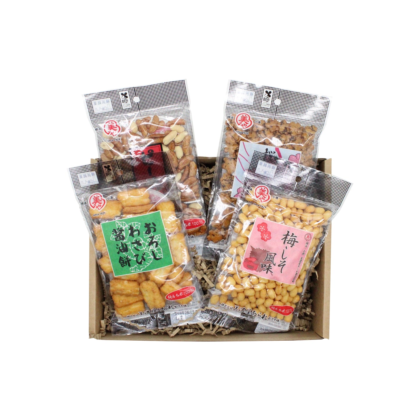 The Japanese Rice Cracker Set includes four bags of assorted Minoya Arare rice crackers in clear packaging with colorful labels, attractively arranged on shredded paper.