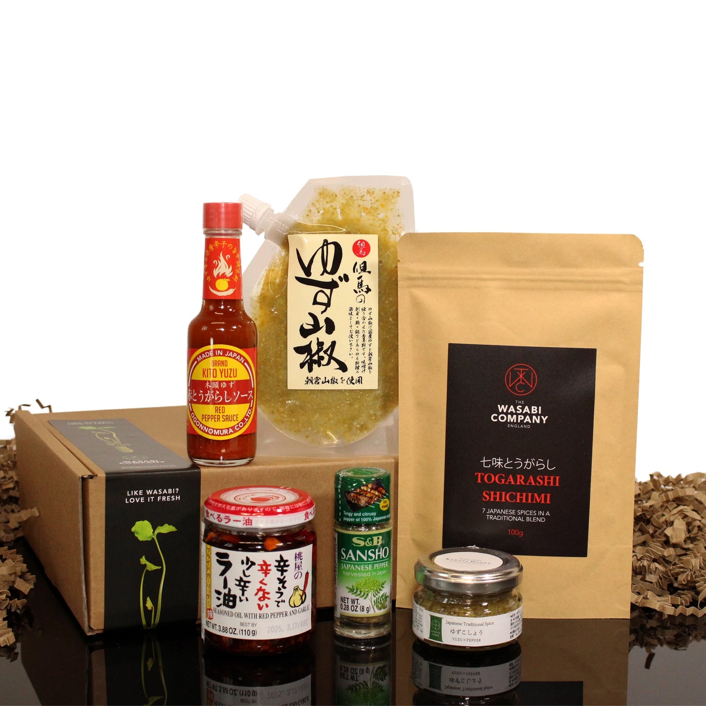 The Japanese Spice Set includes Yuzu citrus juice, Sansho spice mix, La-Yu Chilli Oil, hot sauce, and seasoning jars, displayed on a black surface with a cardboard box.