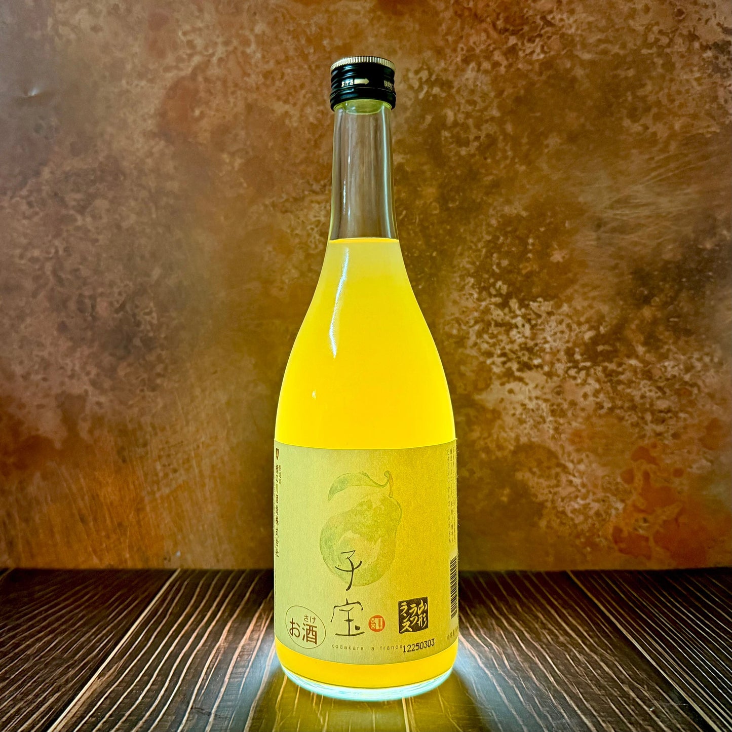 A bottle of Kodakara - Yamagata La France Pear 720ml with a beige Japanese label sits on wood against a brown textured background.