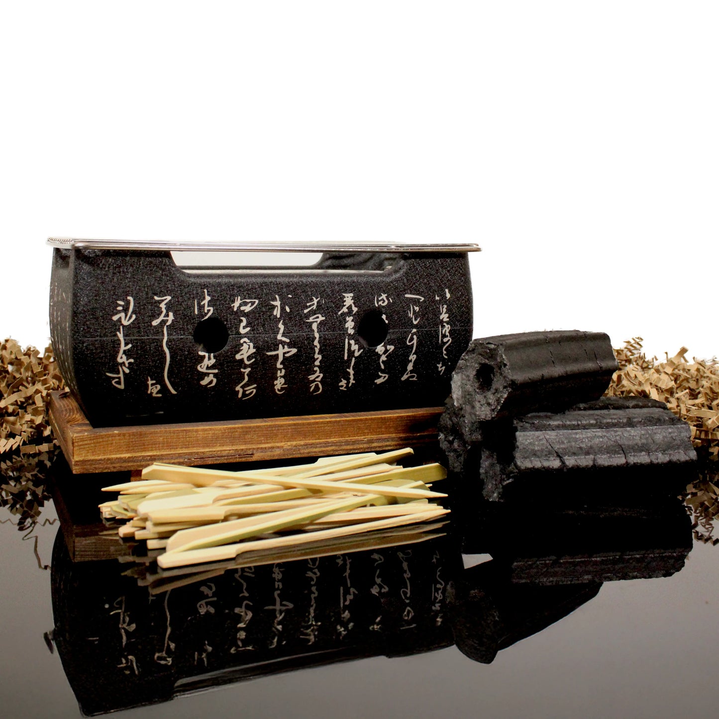 The Konro Aluminium Grill 24cm Barbecue Set features a Japanese-style grill on a wooden base, complete with Binchotan charcoal briquettes and bamboo skewers for an authentic tabletop barbecue experience.