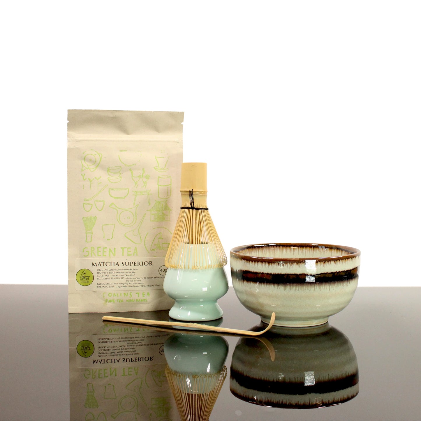 The Matcha Tea Set in Green with Matcha Tea includes premium matcha powder, a ceramic whisk holder, bamboo whisk and scoop, and a matcha bowl, all elegantly arranged on a reflective surface.