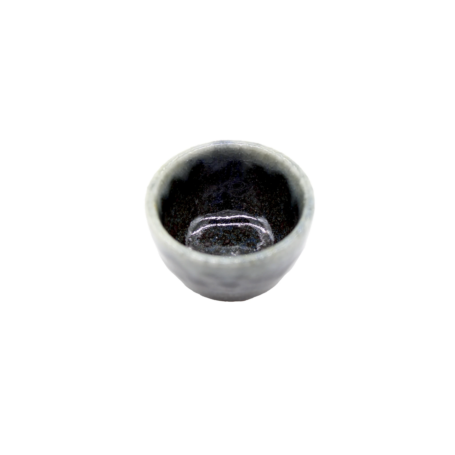The Sake Cup - Dark Blue Glaze with Grey Drip is a small, round Minoyaki porcelain bowl featuring a dark, glazed interior and a light, uneven rim, reminiscent of traditional sake cups, set against a white background.