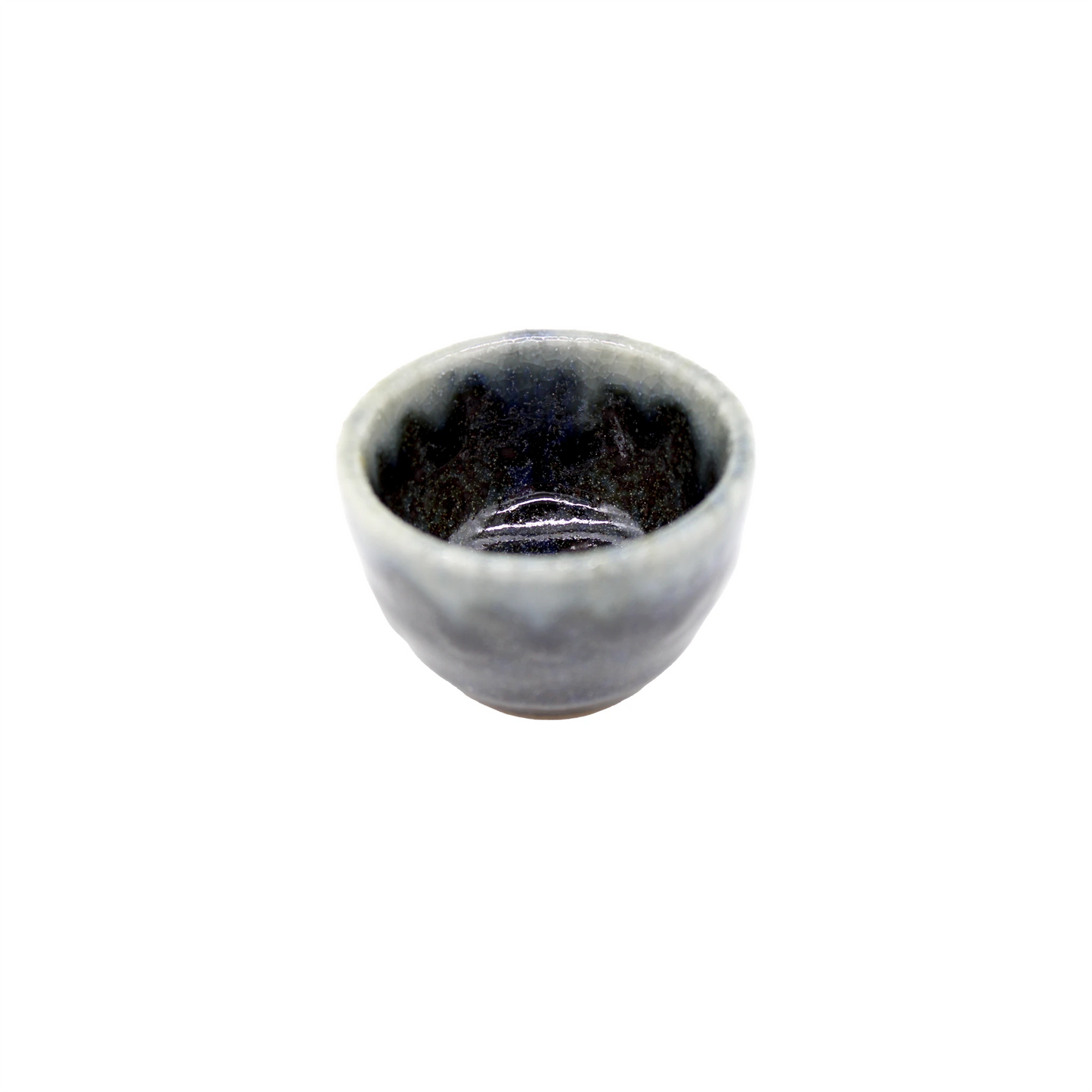 The Sake Cup - Dark Blue Glaze with Grey Drip features a small, round Minoyaki porcelain form, a dark glossy interior, a slightly uneven rim, and is reminiscent of a traditional sake cup. Isolated on white background.
