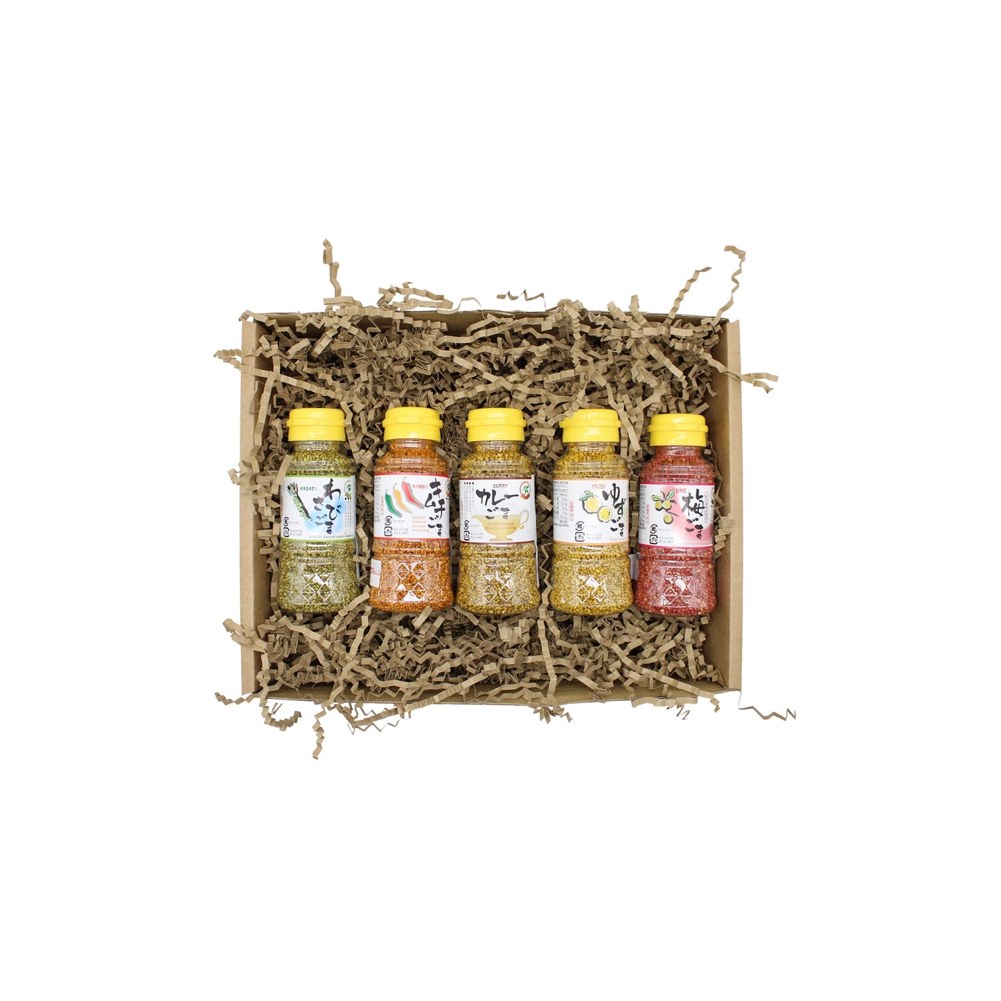 The Sesame Seeds 5 Flavours Set features five bottles with handwritten labels, arranged in a gift box filled with shredded brown packing paper, viewed from above on a white background.