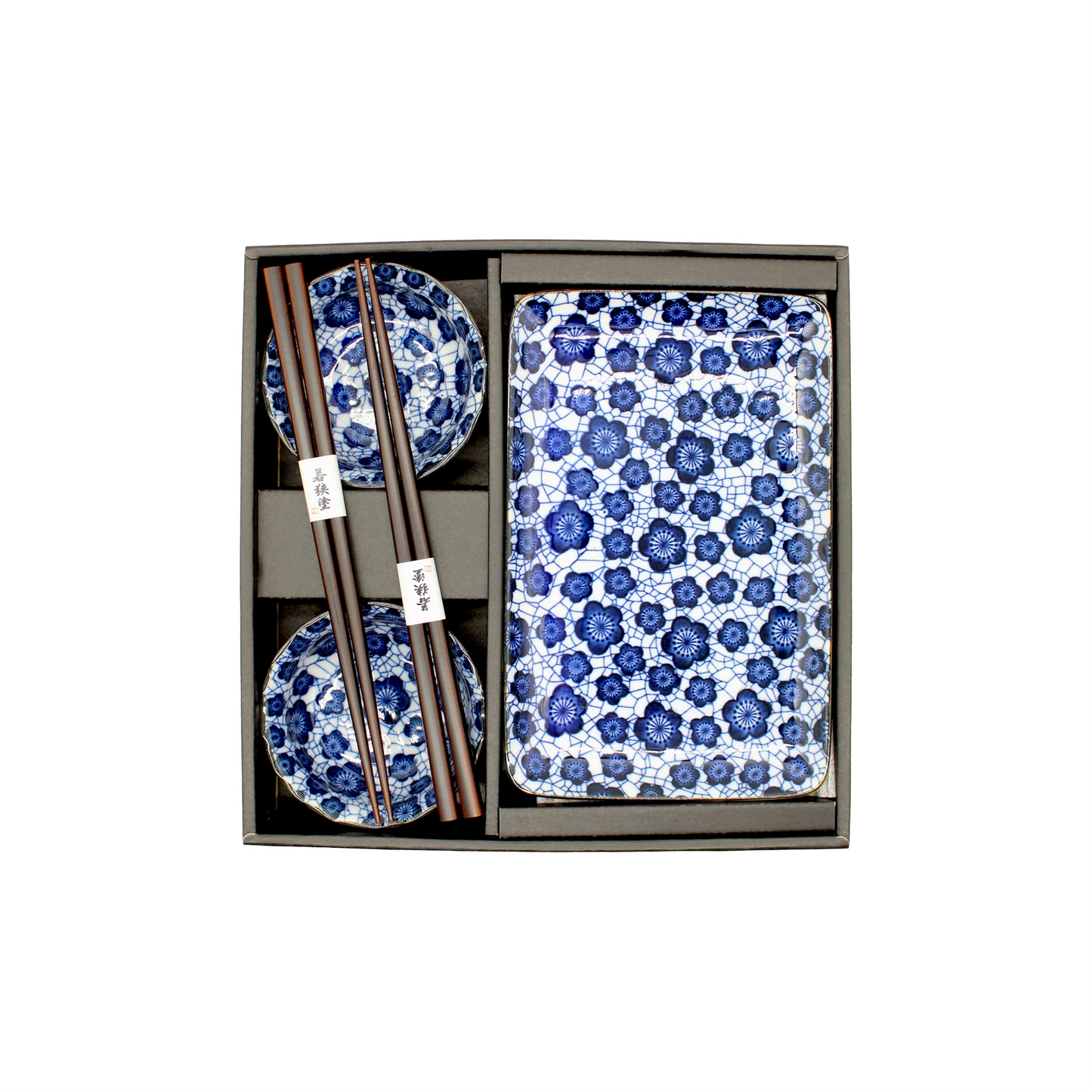 The Sushi Gift Set in Blue Plum includes two blue and white patterned bowls, two pairs of chopsticks, and a matching rectangular plate with Japanese design, all elegantly arranged in a sleek black tray.