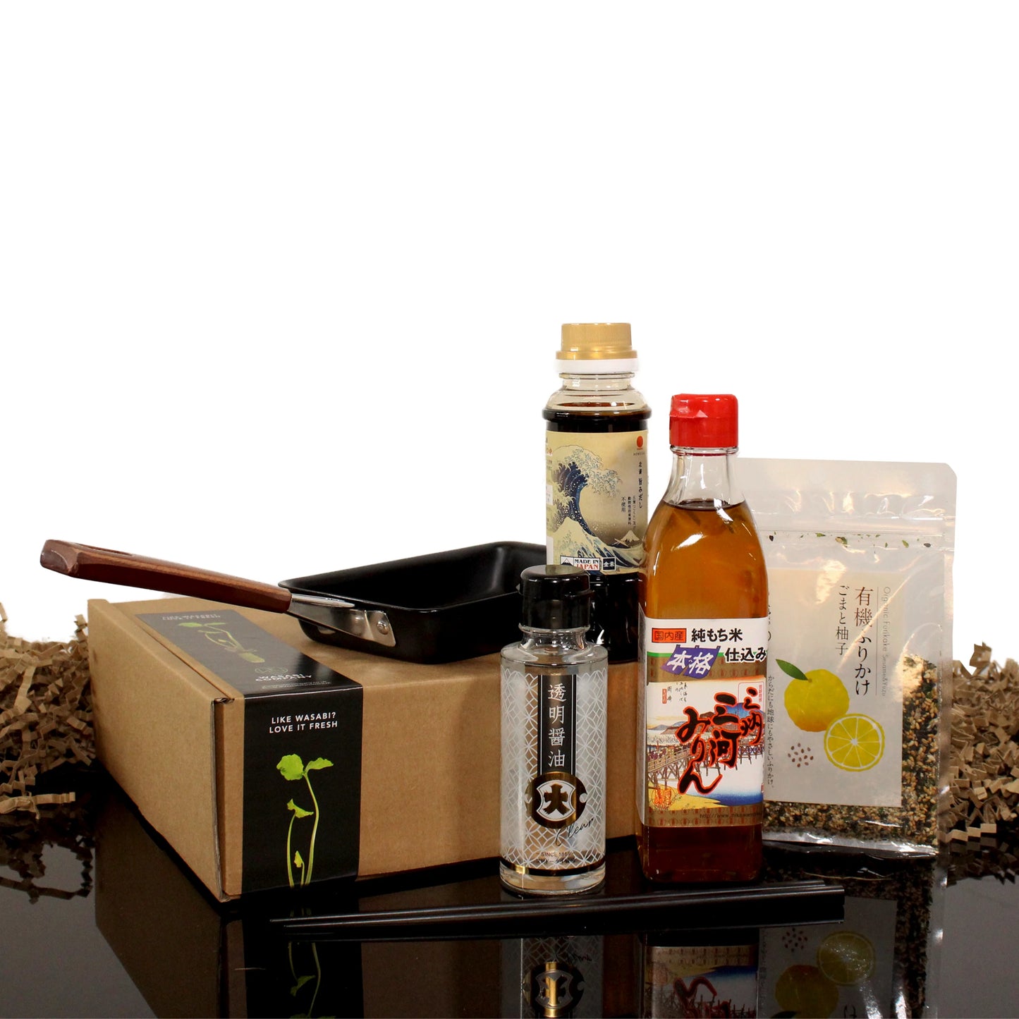 The Tamagoyaki Breakfast Kit includes a tamagoyaki pan, chopsticks, sauce bottles, a spice jar, and a pouch—all neatly arranged beside a cardboard box for the perfect Japanese breakfast experience.