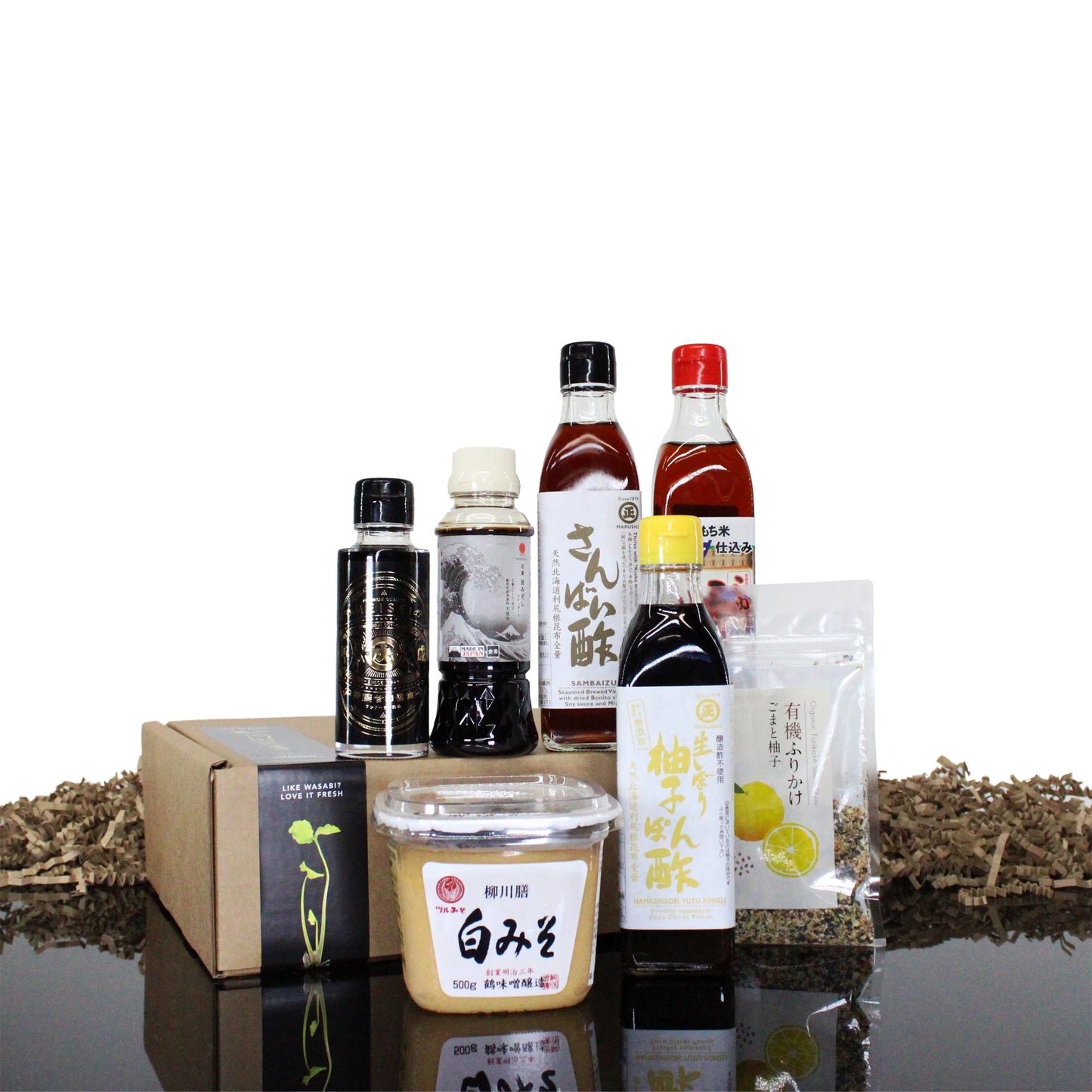 The Ultimate Japanese Cooking Collection features miso paste, sauces, mirin, vinegar, seasoning packets, and a boxed item, attractively arranged on a white background with decorative filler.
