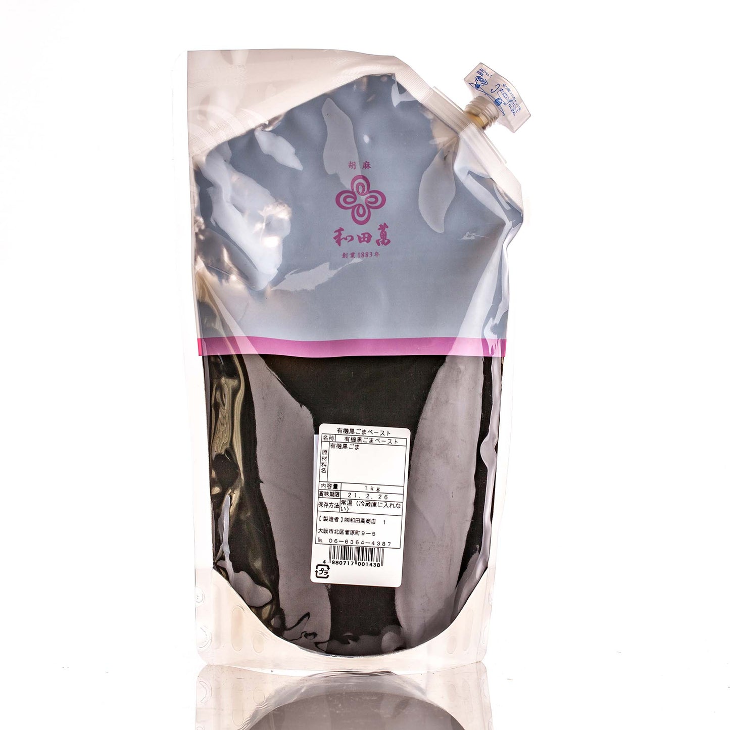 A stand-up pouch labeled Wadaman Organic Black Sesame Paste with Japanese text contains a dark liquid paste; it features a screw cap and displays nutritional information on the back.