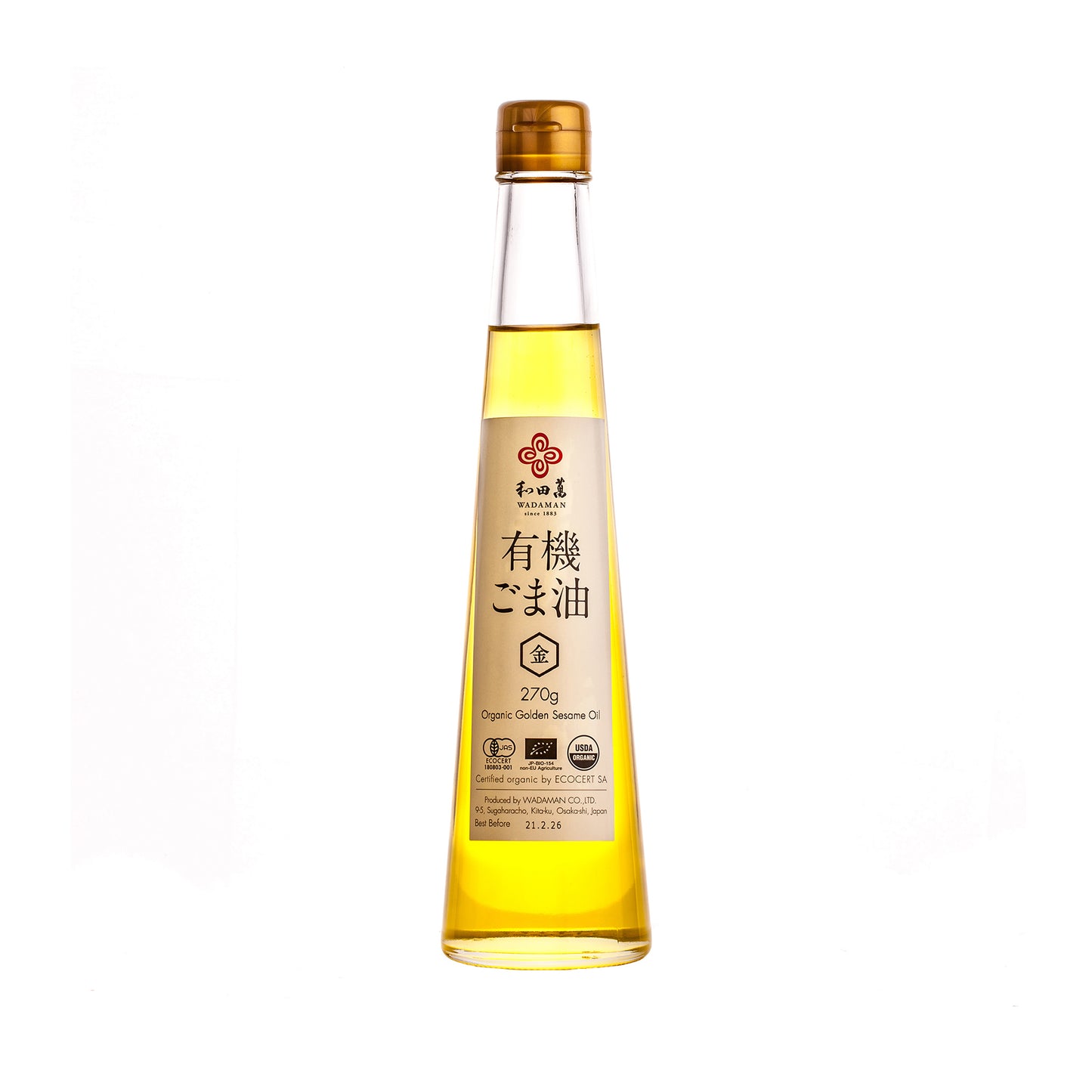 A clear glass bottle of Wadaman Organic Gold Sesame Oil, made from organic gold sesame seeds by master roaster Etsuji Wada, with a gold cap and a label displaying both Japanese and English details.