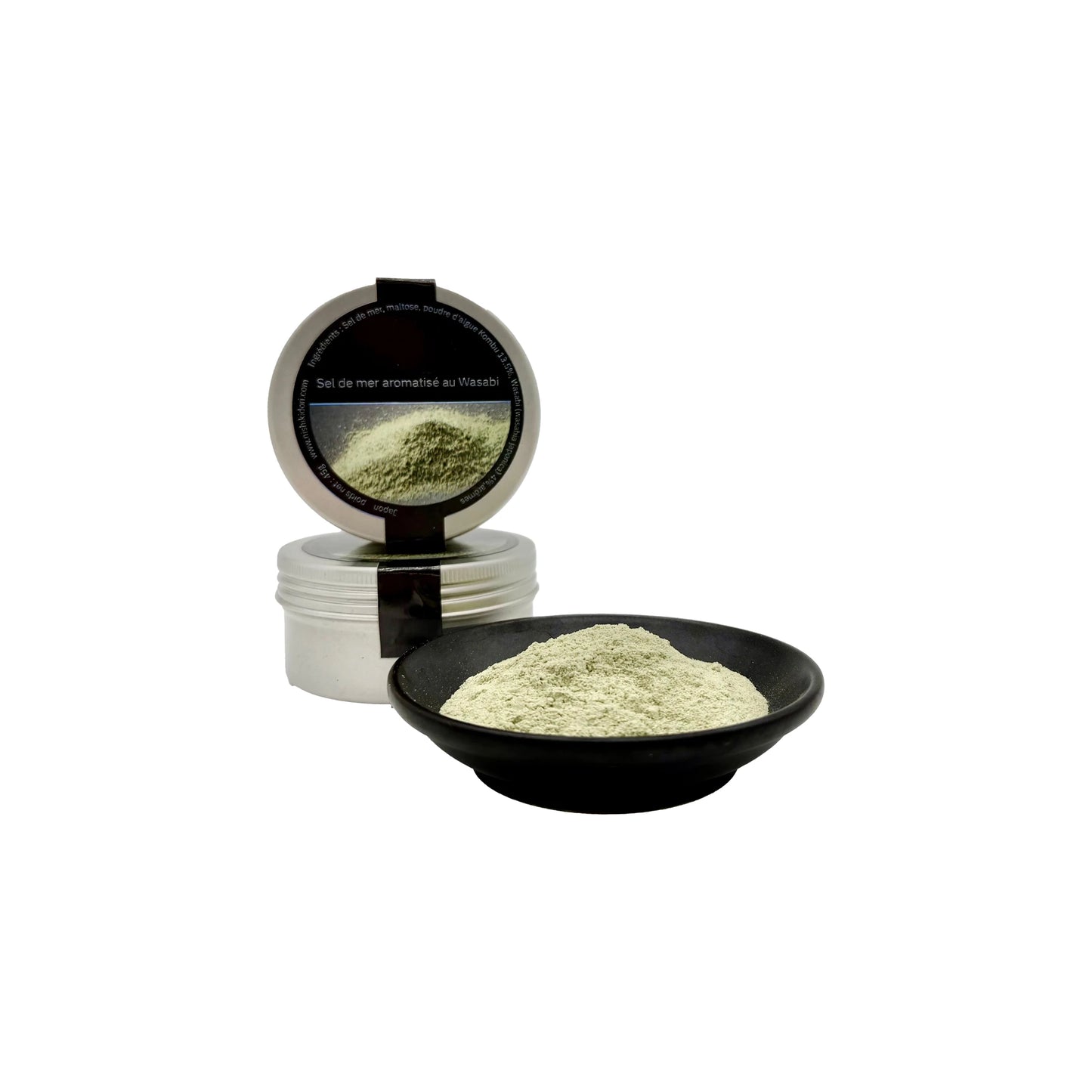 A small black dish with greenish powder sits before an open Wasabi Sea Salt - 45g container, showcasing wasabi salt blended with kombu kelp to deliver a rich umami flavor.