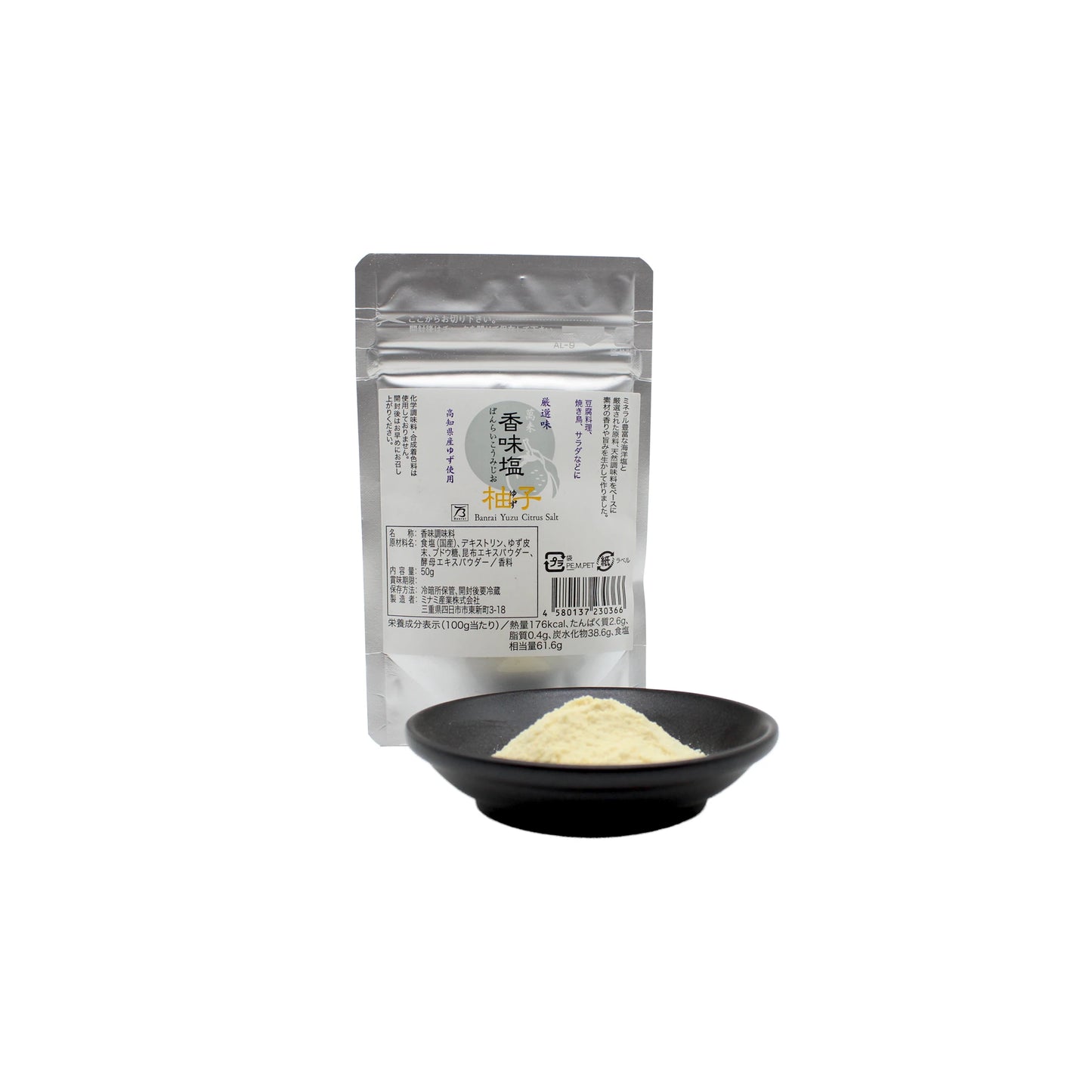 A small black bowl with pale yuzu-flavored sea salt sits before a standing silver packet labeled Yuzu Flavoured Sea Salt - 50g, featuring Japanese writing that suggests premium flavors from Kôchi.