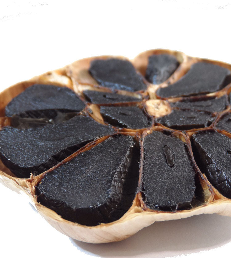 A close-up of a halved Black Garlic Bulb - Each shows its glossy, dark cloves in a circular pattern, highlighting the rich transformation from fermentation—a specialty crafted in Dorset.