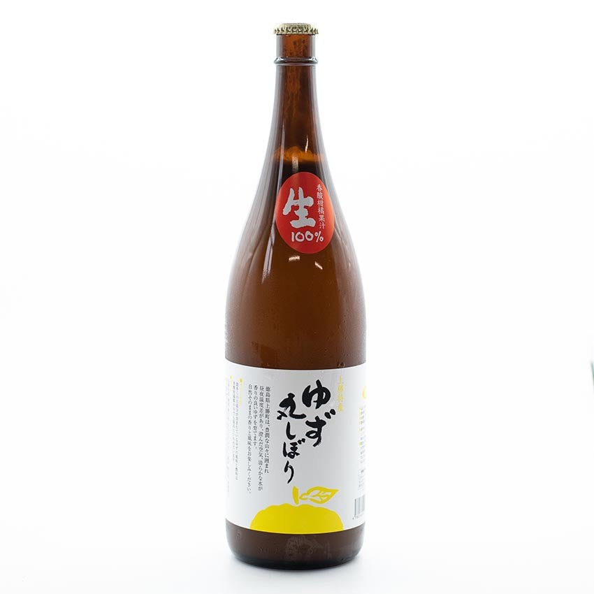 Fresh Yuzu Juice from Tokushima - 1.8L comes in a brown glass bottle with a white label featuring Japanese text, a yellow yuzu fruit illustration, and a red 100% premium yuzu juice sticker, celebrated for its vibrant citrus aroma and tart flavor.