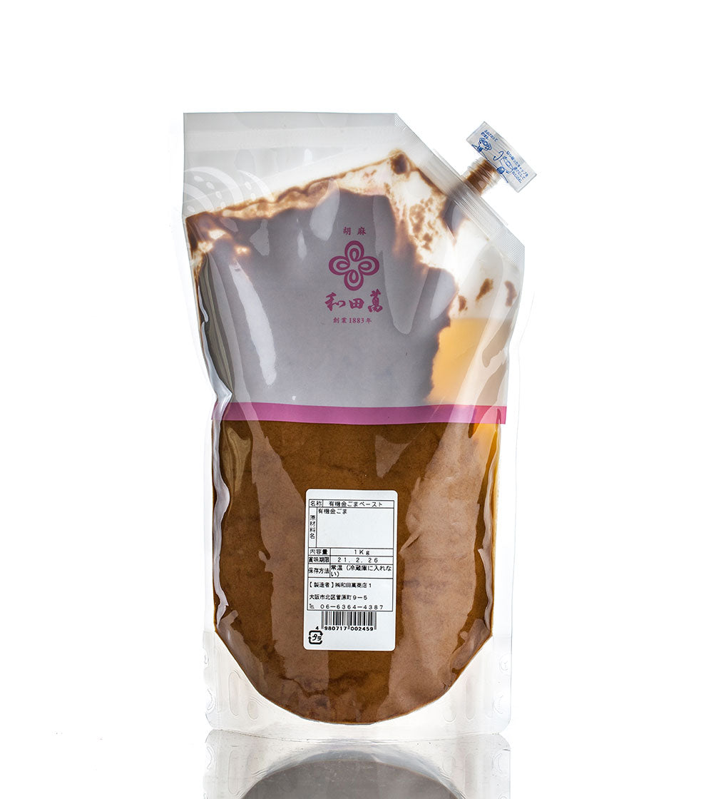 A sealed, transparent plastic pouch labeled in Japanese contains Wadaman Organic Gold Sesame Paste—brown powder made from gold sesame seeds—with a nutritional information panel.