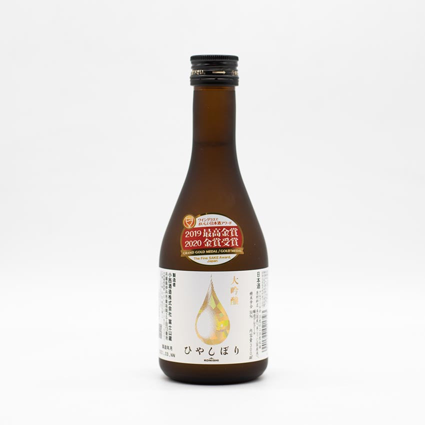 A brown glass bottle of Konishi Gold - Daiginjo, with Japanese text and Fine Sake Awards gold stickers on the neck, displayed against a plain white background.