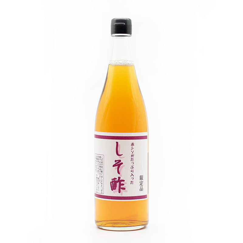 A clear glass bottle of Red Shiso Rice Vinegar (720ml), filled with light amber liquid, crafted by a master vinegar maker, features a white label with Japanese text and a black cap, set against a plain white background.