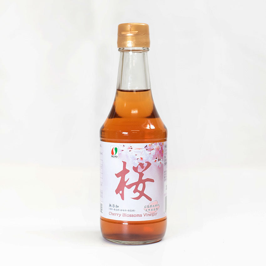 Sakura Cherry Blossom Vinegar - 300ml comes in a clear glass bottle with a gold cap, adorned with a white and pink label featuring Japanese writing and cherry blossom imagery.