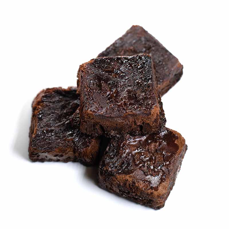 Four pieces of rich, dense chocolate brownies—enhanced with a hint of 3 Year Aged Soy Freeze Dried 30g—are stacked on a white background.