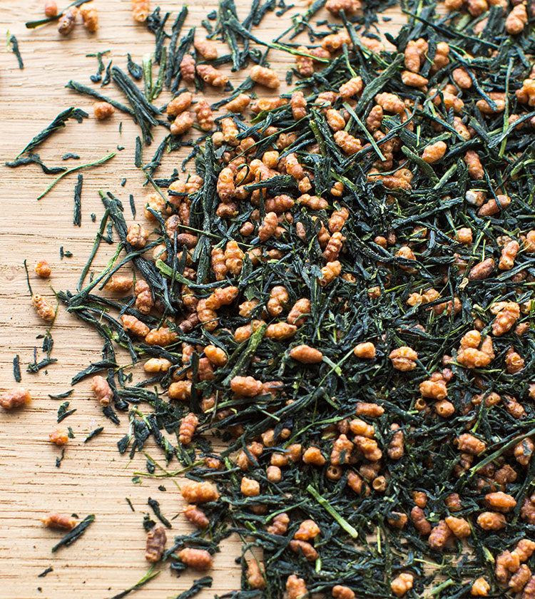 Genmaicha Tea - 50g, a blend of loose tea leaves and roasted brown rice with premium sencha, is displayed on a wooden surface.