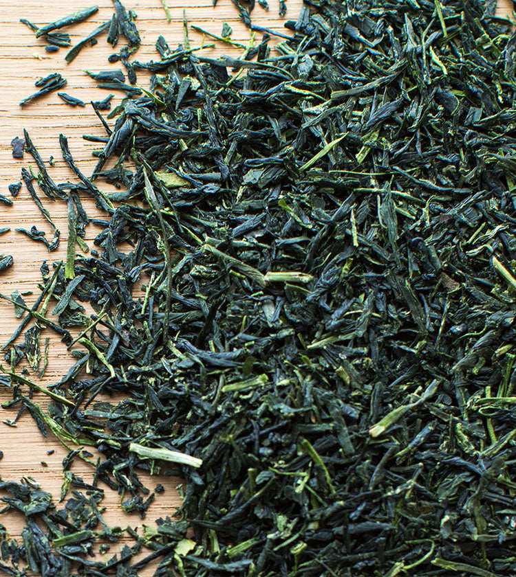 Gyokuro Tea - 50g, celebrated for its natural sweetness, is displayed as loose-leaf green tea spread out on a wooden surface.