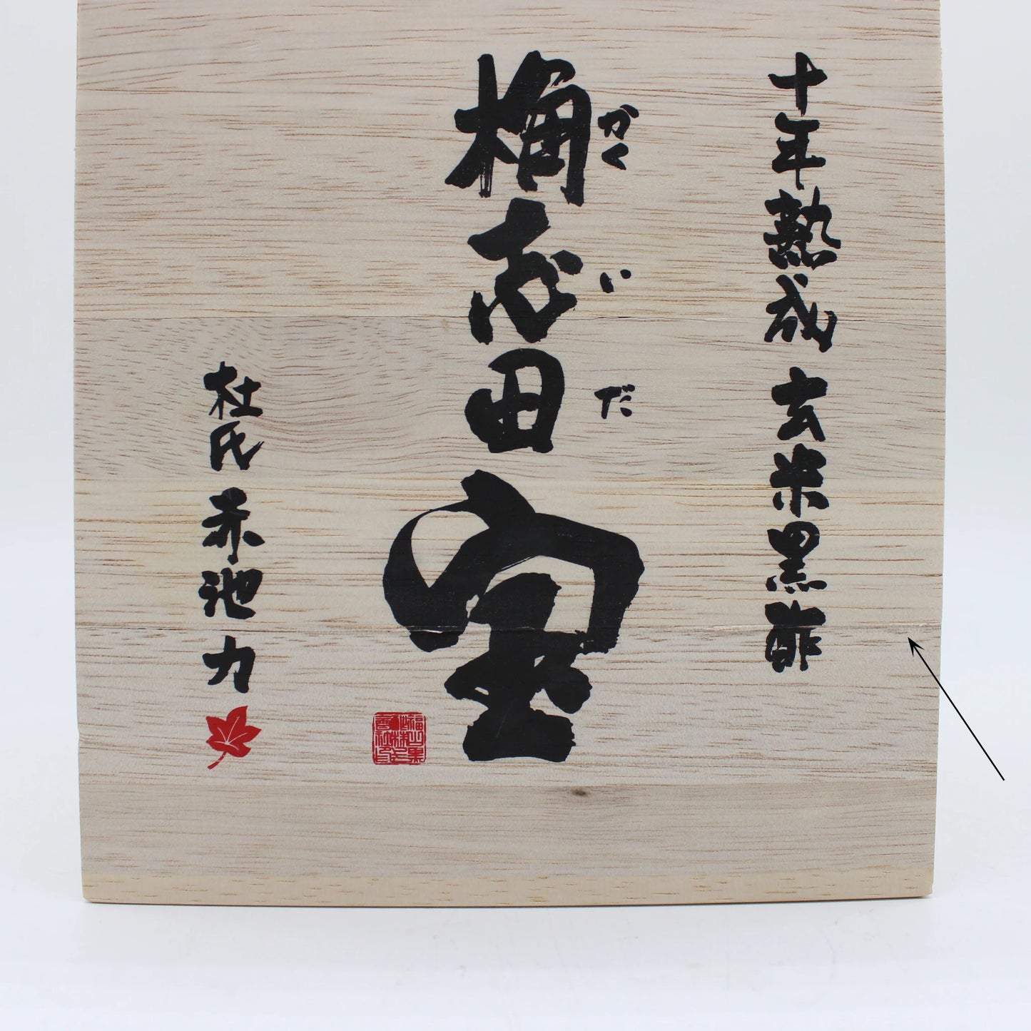 
                  
                    A wooden box with Japanese calligraphy, red stamps, black vertical and horizontal text, and a small red maple leaf symbol contains authentic 10 Year Aged Black Rice Vinegar – 1L On Offer from Kagoshima.
                  
                