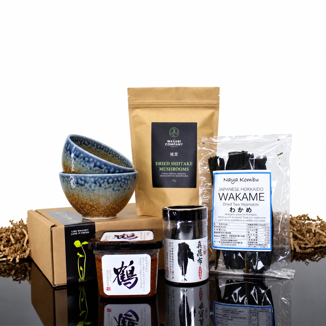 Vegan Miso Soup Kit with Miso Bowls including two speckled ceramic bowls, a pouch of shiitake mushrooms, a container of miso paste, a jar of kombu, and a bag of dried wakame seaweed.