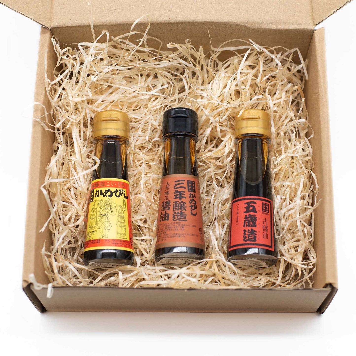
                  
                    The Aged Soy Sauce Triple Pack features three bottles of premium soy sauce, celebrated for their rich umami flavor, neatly arranged in a straw-filled cardboard box.
                  
                