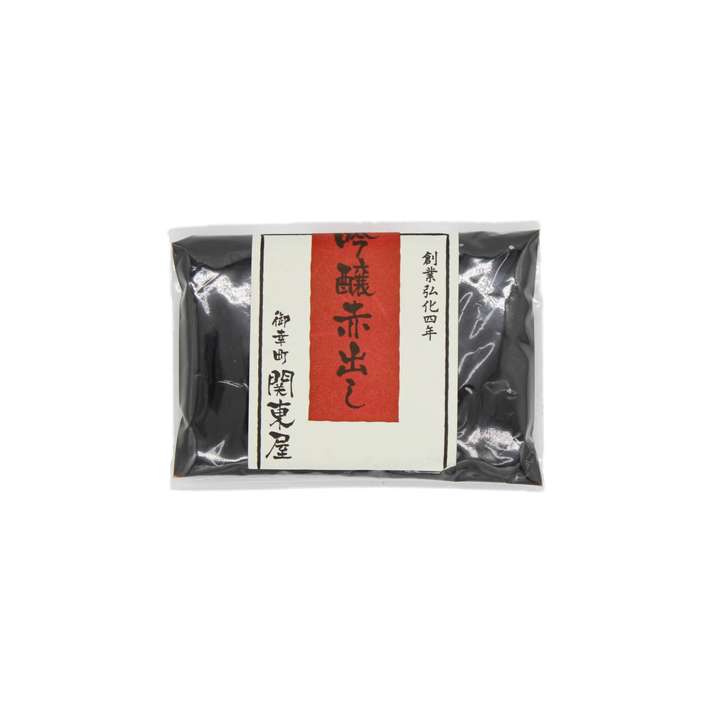 A sealed package of Aka Dashi Red Miso (100g) with a white label, red vertical strip, and black Japanese kanji highlights the rich umami flavor of this Japanese food product.