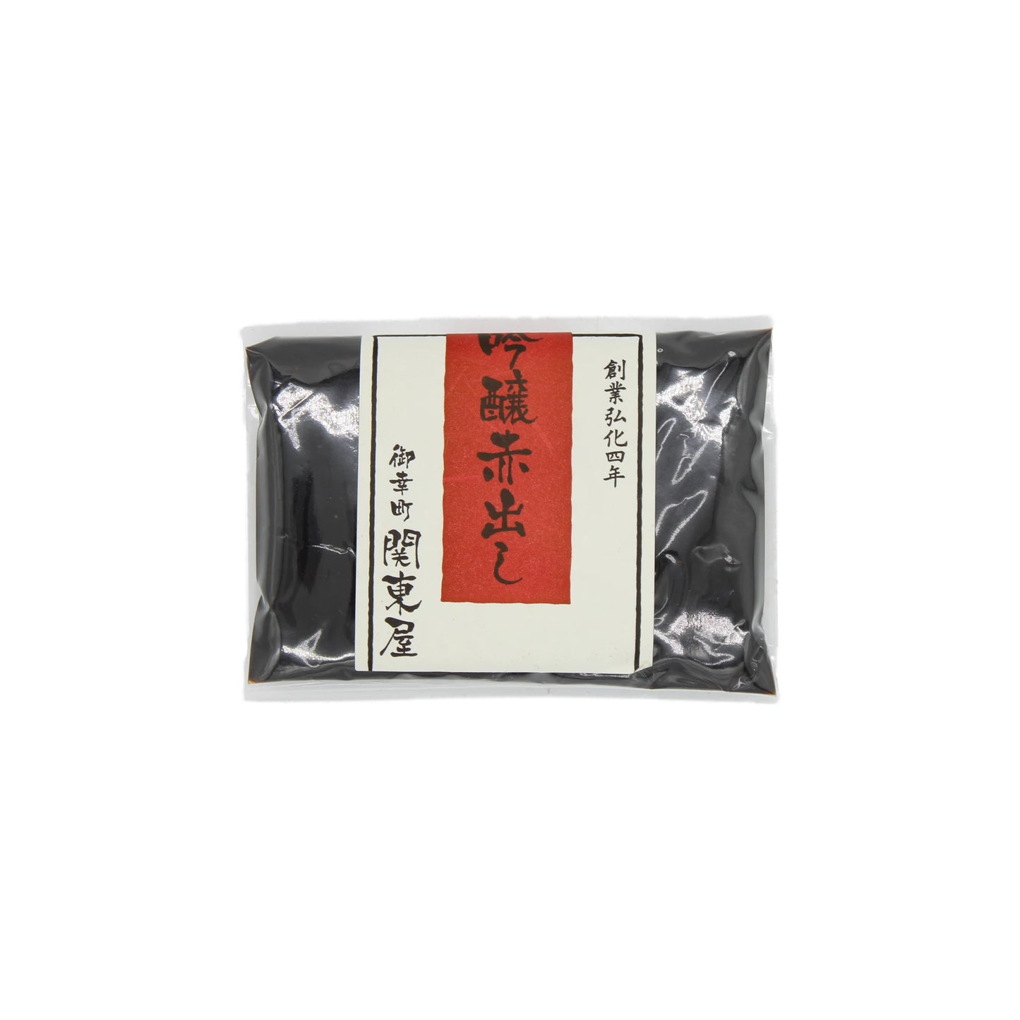 A sealed package of Aka Dashi Red Miso (100g) with a white label, red vertical strip, and black Japanese kanji highlights the rich umami flavor of this Japanese food product.