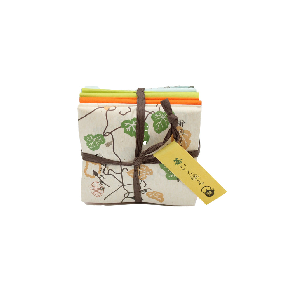 A neatly folded bundle of patterned cloths tied with brown string and a yellow tag with Japanese writing—perfect for gifting alongside the Japanese Tea Assortment (8 bags, 4 different teas).