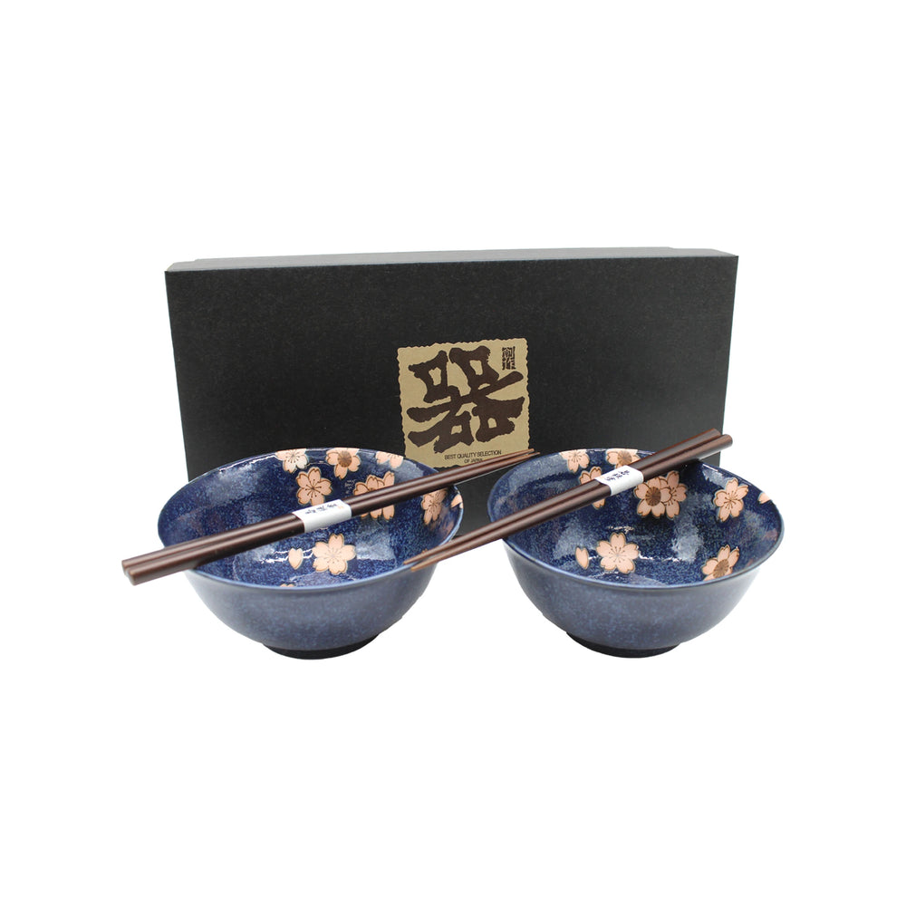Two Cherry Blossom Bowls Boxed Set – Blue with Pink Sakura, featuring floral patterns and paired with brown chopsticks, elegantly displayed in front of a black box with a gold Japanese label—a stunning example of Mino ware ceramics.
