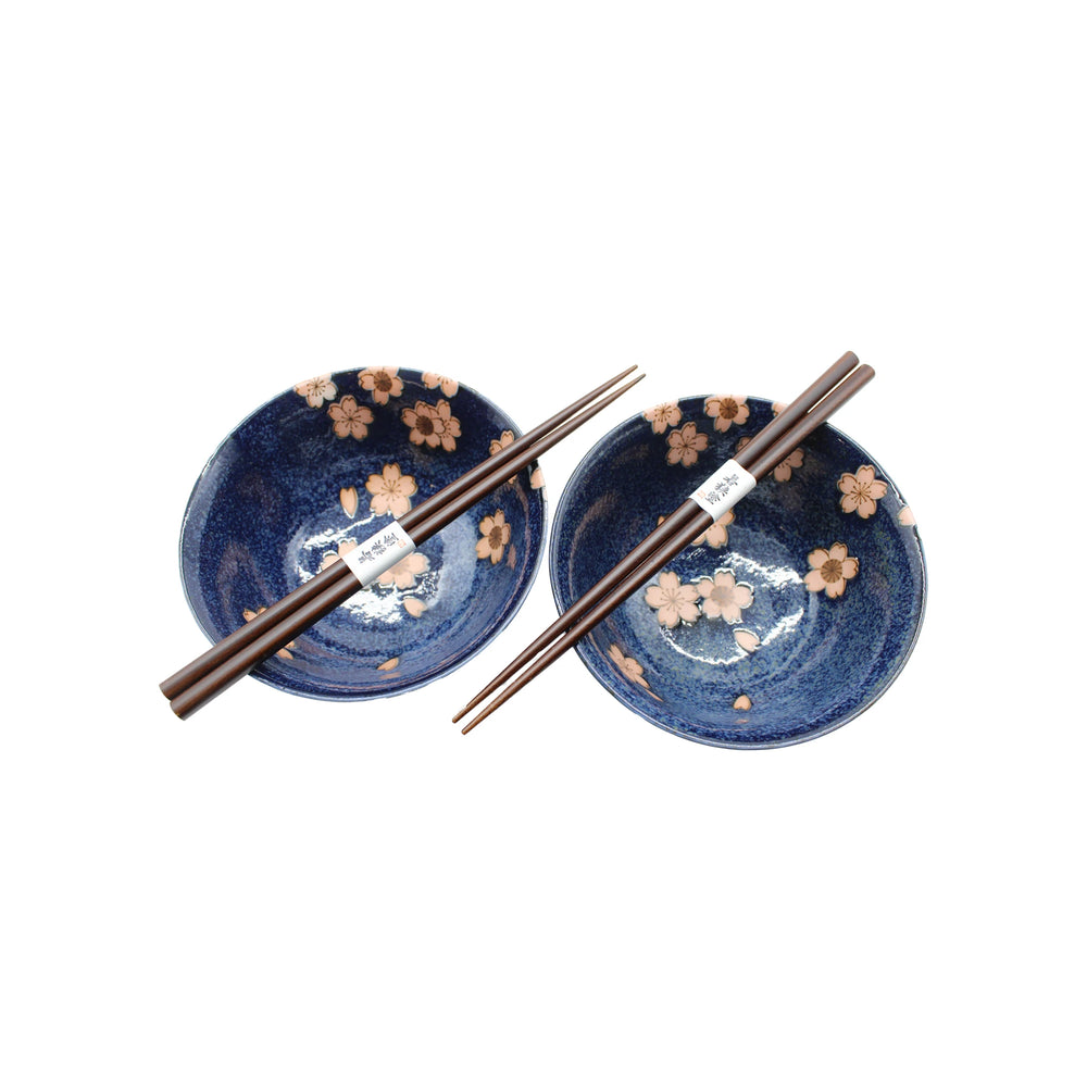 The Cherry Blossom Bowls Boxed Set - Blue with Pink Sakura features two bowls with pink sakura designs, each paired with wooden chopsticks, beautifully displayed on a white background—a stylish tribute to Japanese ceramics.
