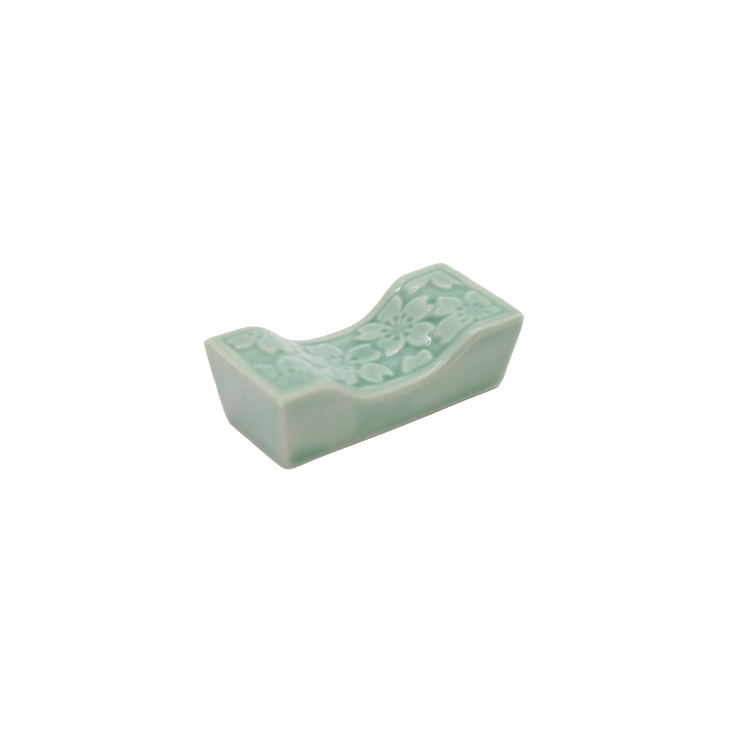 The Chopstick Rest - Sakura Pattern in Celadon Green is a small ceramic rest featuring a delicate floral sakura design on top, shown on a white background.