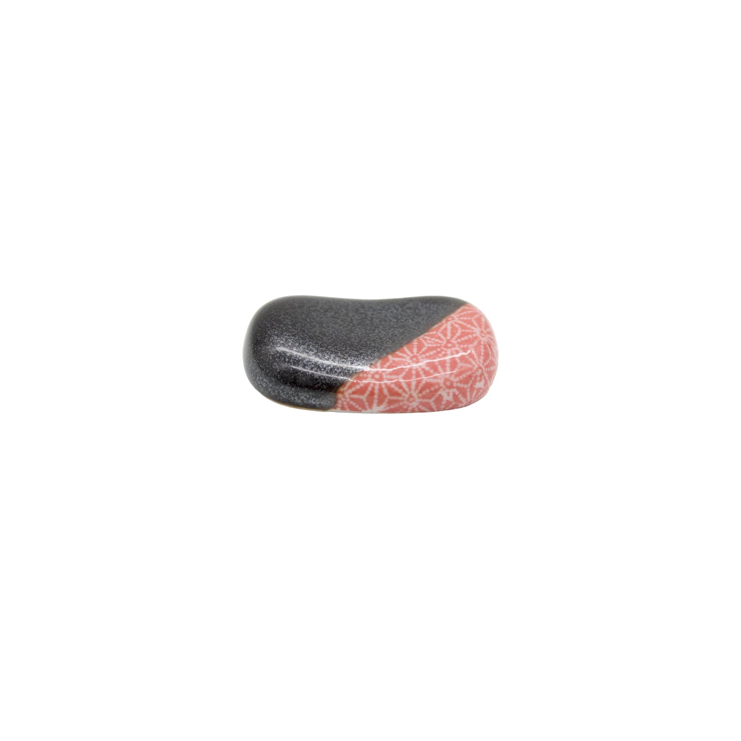 A small, smooth Chopstick Rest called Pebble in gunmetal grey with one side decorated in coral and a white Japanese star pattern, displayed on a white background.
