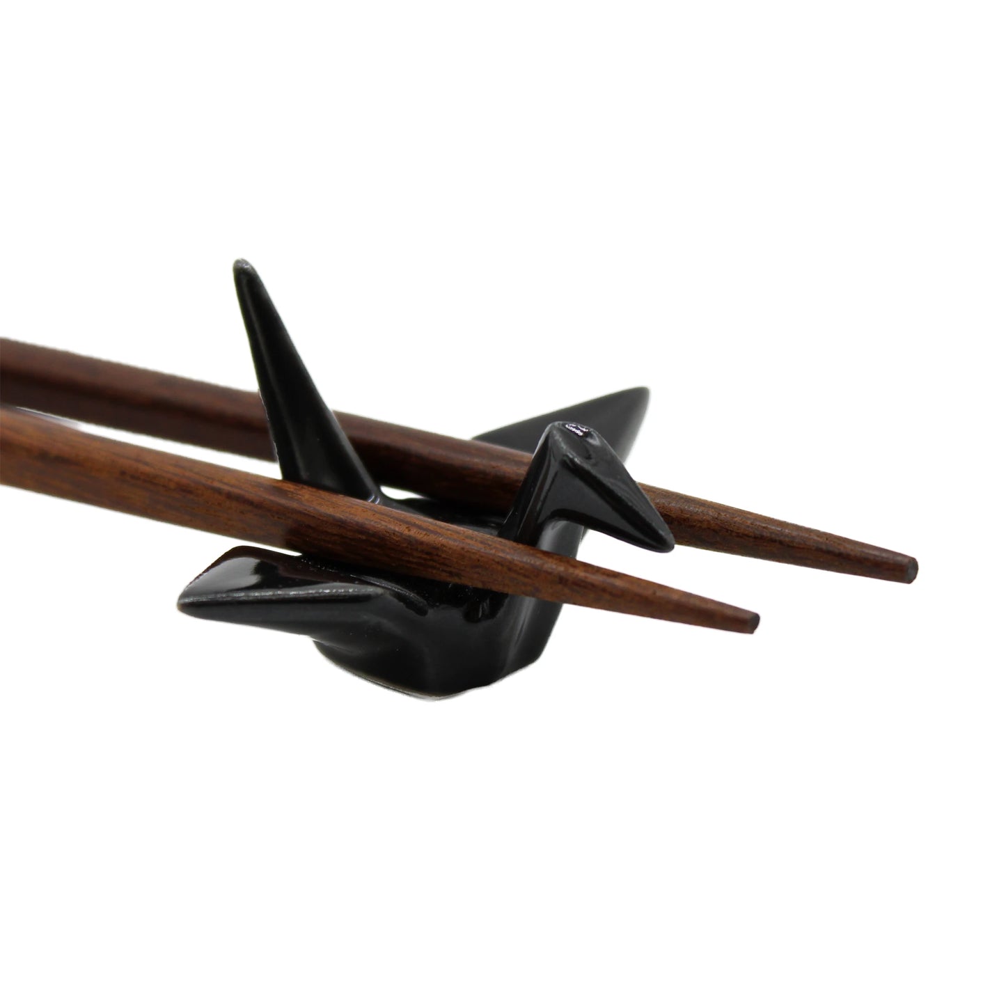 A pair of wooden chopsticks rests on the Chopstick Rest - Origami Crane Black, highlighting Japanese elegance against a white background.