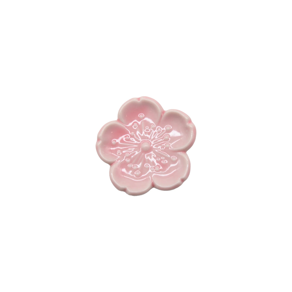 
                  
                    The Chopstick Rest - Pink Sakura is a small, pink Minoyaki porcelain dish shaped like a five-petal flower with embossed details in the center, inspired by Japanese tableware and shown on a white background.
                  
                