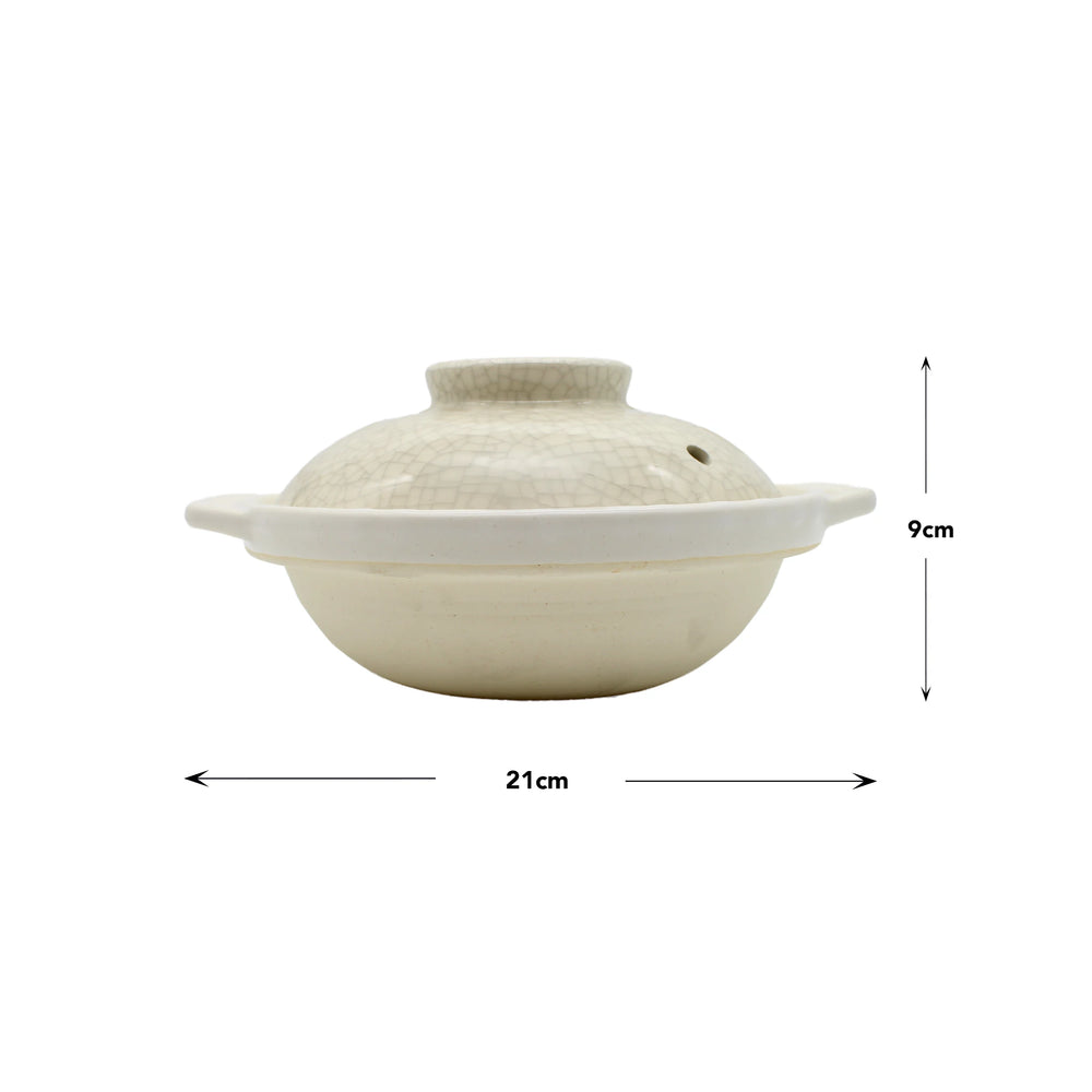 
                  
                    The Donabe Pot - Cream with Crackle Glaze features a lid, side handles, and a crackle glaze finish. It measures 21 cm wide by 9 cm high, as shown by the labeled arrows.
                  
                