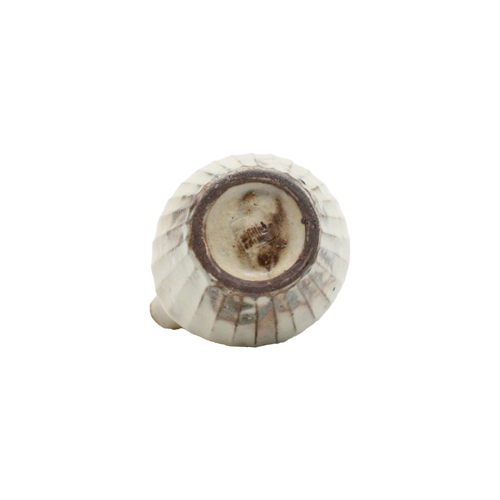 
                  
                    The Pourer - Iron Scatter features a round ceramic shape with vertical ridges, a rustic unglazed base, and central metal attachment point—crafted in the Shigaraki pottery style.
                  
                