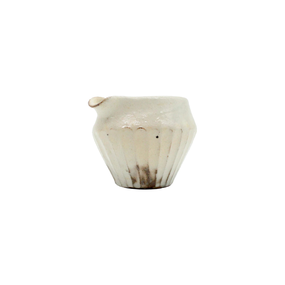 
                  
                    The Pourer - Iron Scatter is a small, white ceramic creamer with a fluted body and short spout, inspired by Japanese pourer designs, photographed against a plain white background.
                  
                