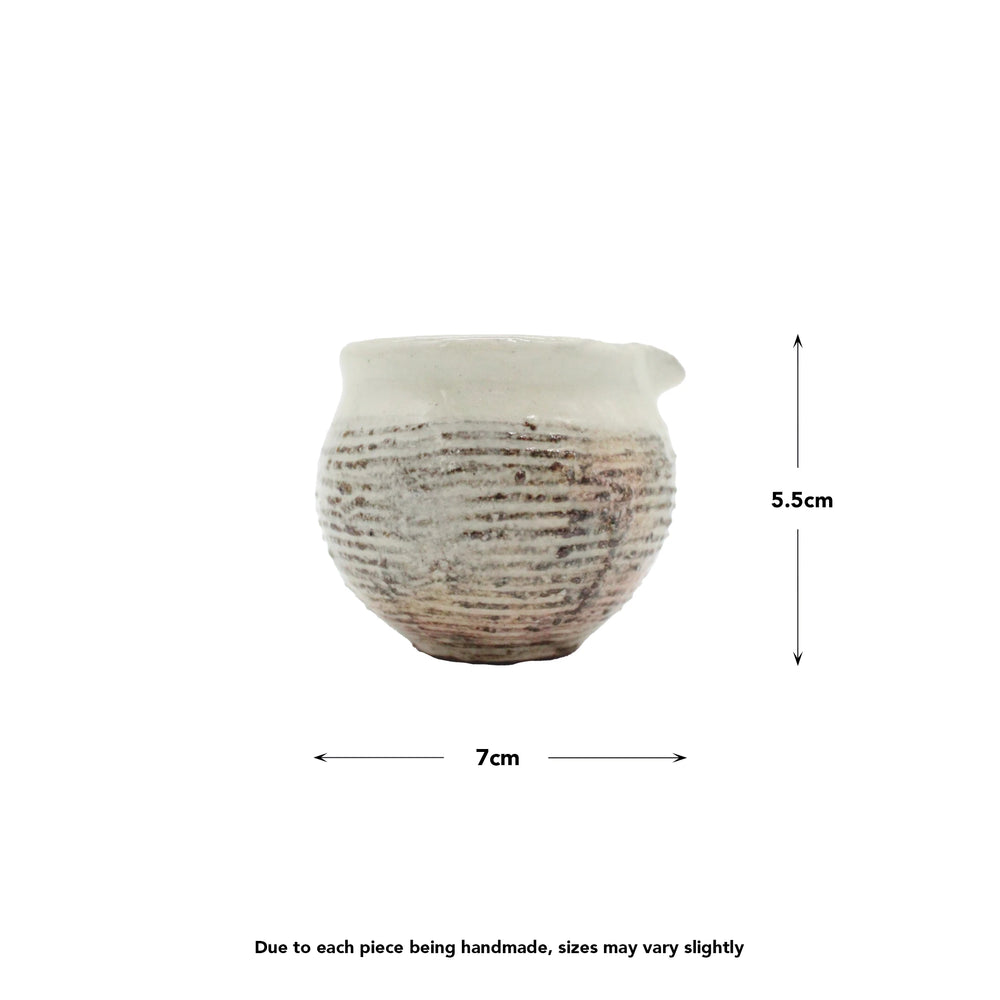 
                  
                    The Pourer - Fuchiara Carved is a handmade ceramic pourer inspired by Shigaraki pottery, featuring a textured surface and measuring 7 cm wide by 5.5 cm high—size may vary slightly due to its artisanal nature.
                  
                