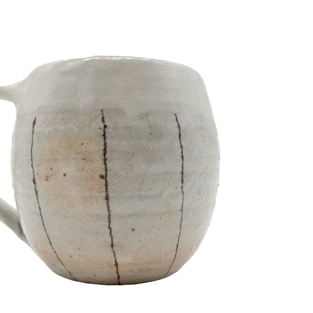 
                  
                    The Tea Mug with Handle - Iron Wire is a handmade ceramic mug inspired by Japanese Shigaraki pottery, featuring a matte off-white finish, visible ridges, and vertical black lines for a traditional look.
                  
                
