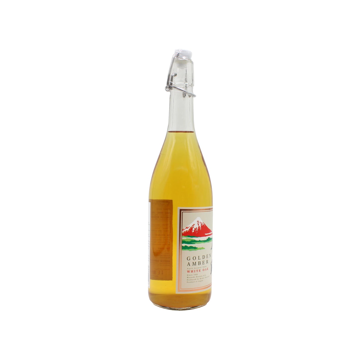 A clear glass bottle with a swing-top cap, filled with golden liquid. The label reads “Golden Amber - Aged Koshu Junmai Sake - 720ml” and features a mountain landscape—an oak barrel aged sake inspired by Japanese tradition.
