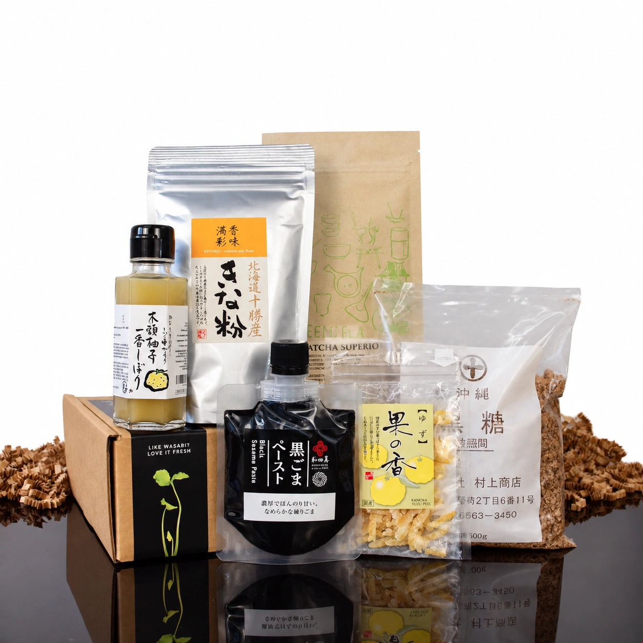 The Japanese Baking Collection featuring matcha, yuzu, citrus dressing, flour, sesame paste, and brown sugar arranged in and around a cardboard box.