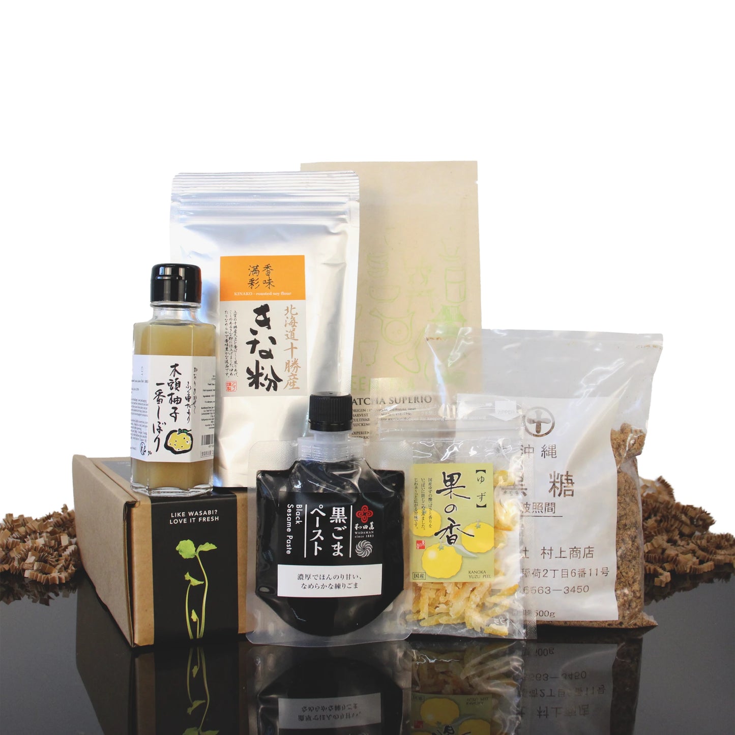 The Japanese Baking Collection includes yuzu juice, roasted soy flour, black sesame paste, dried yuzu peel, and brown sugar arranged in and around a cardboard box.