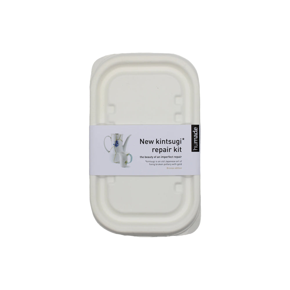 
                  
                    A white container labeled Kintsugi Kits - Gold, Silver & Bronze displays a repaired ceramic with a metallic finish, perfect for mending and transforming broken ceramics into unique pieces.
                  
                