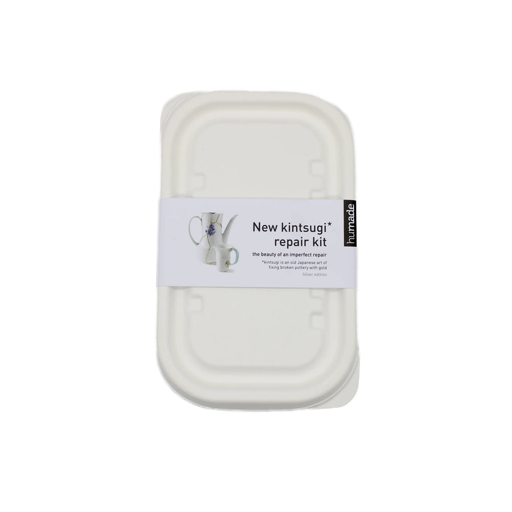 
                  
                    A white rectangular Kintsugi Kits - Gold, Silver & Bronze container features a label with a ceramic object mended in metallic finish and product information.
                  
                